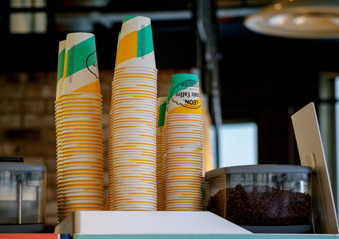 Stacks of colorful paper cups with containers of coffee beans create a cozy café vibe.